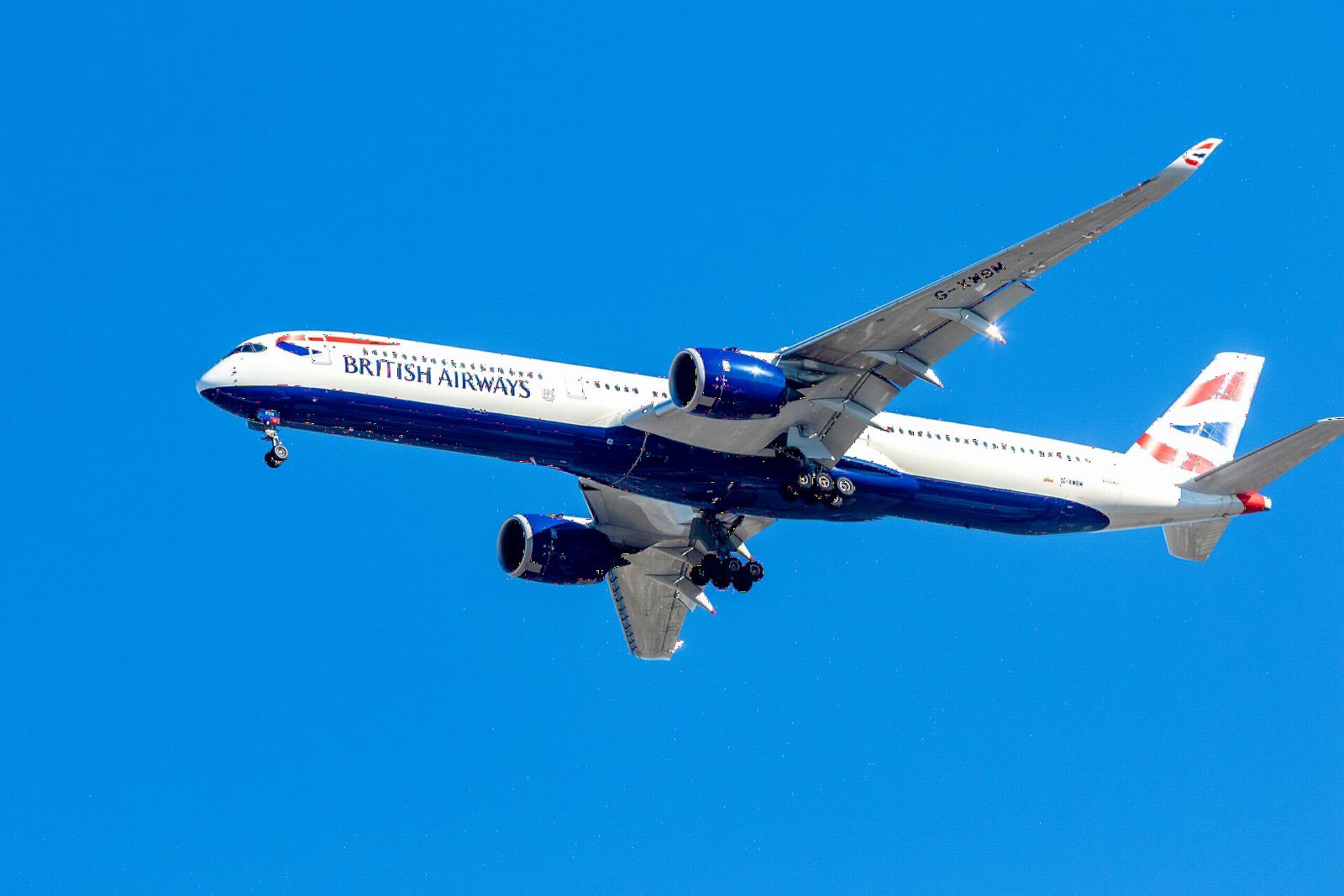 British Airways Airbus A350-1000 flying overhead against a deep blue sky